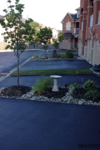 Three freshly paved driveways, separated by strips of grass and rocks leading up to townhouses