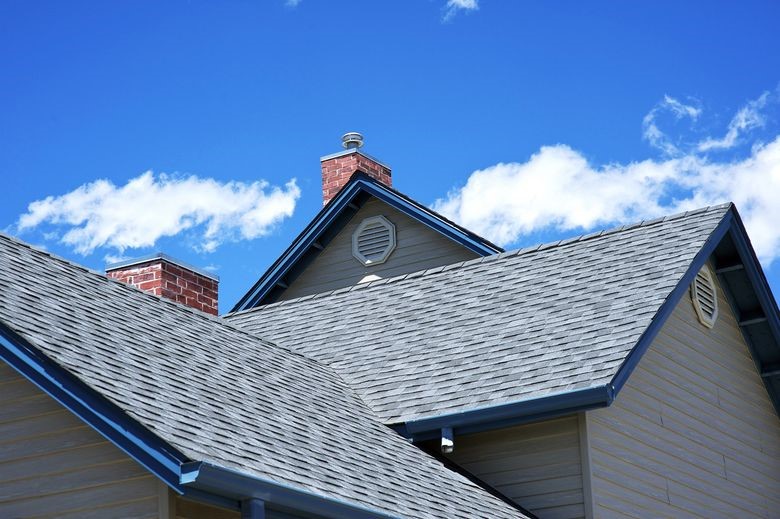A new roof with black asphalt shingles against a clear blue sky